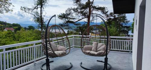 two swing chairs on a balcony with a view at Top Holiday Kuca sa bazenom in Lukavac