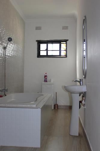 a white bathroom with a tub and a sink at Blue Agave MH in Lusaka