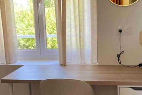 a table with a chair in front of a window at L'Or Miroir - Madame Conciergerie in Bruz