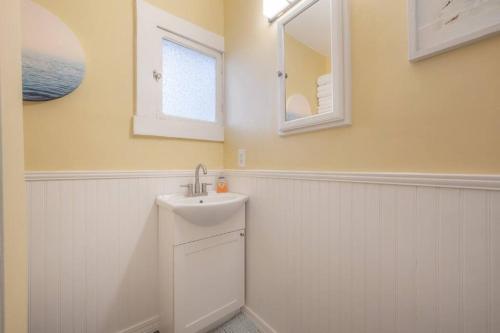 een witte badkamer met een wastafel en een spiegel bij Serene Beachy Bungalow with Large Screened Porch! in Tampa