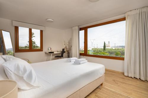 a white bedroom with a large bed and windows at Eliva house in Chania Town