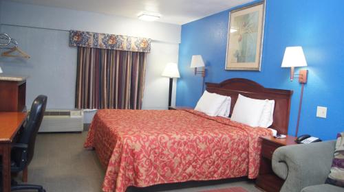 Habitación de hotel con cama y paredes azules en Holiday Lodge & Suites en McAlester