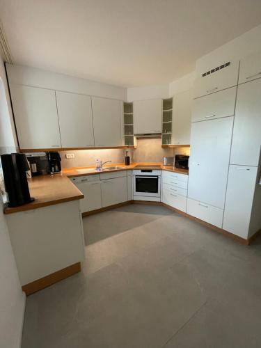 a large white kitchen with white cabinets and appliances at FeWo-Julius am Weser-Sandstrand in Berne