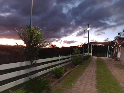a fence in front of a building with a cloudy sky at Chalés do Apolinário in Tiradentes