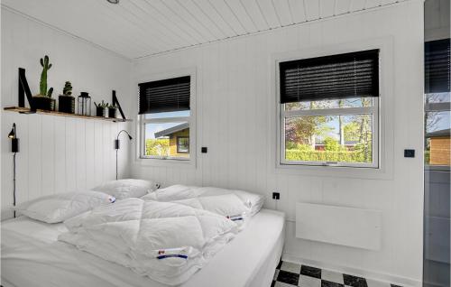 ein weißes Schlafzimmer mit einem Bett mit weißer Bettwäsche und Fenstern in der Unterkunft 4 Bedroom Stunning Home In Bogense in Bogense