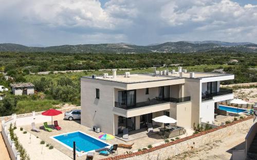 una casa grande con piscina frente a ella en Villa Adriatic Sunrise, en Šibenik