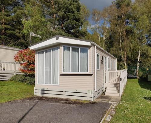 a small white shed with windows in a yard at Calm & Cosy (sleeps up to 6) - Oakdene Forest Park in Ferndown