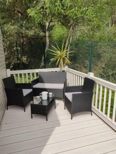 a porch with two chairs and a table on a deck at Calm & Cosy (sleeps up to 6) - Oakdene Forest Park in Ferndown