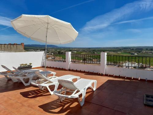 un patio con mesa, sillas y sombrilla en Lonja del Ribacillo, Casa Rural en Almodóvar del Río