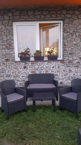 a group of chairs and a table in front of a stone wall at Apartmani Vesna in Novi Sad