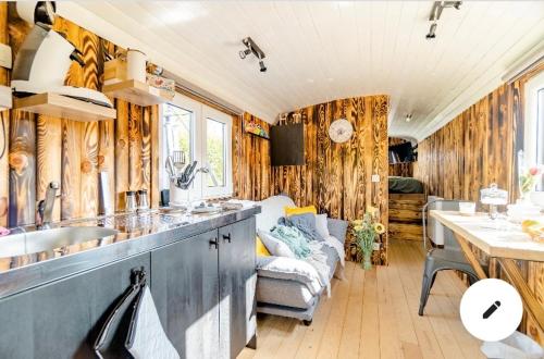 a kitchen and living room in a trailer with wooden walls at Roulotte du puits avec jacuzzi et sauna privatif 