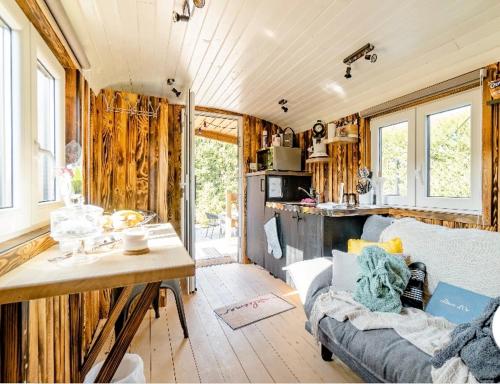 een woonkamer met een bank en een keuken met ramen bij Roulotte du puits avec jacuzzi et sauna privatif 