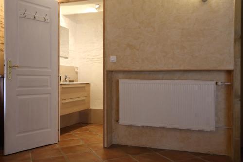 une salle de bains avec un radiateur blanc à côté d'une porte dans l'établissement les Tours de Bombel, à Saint-Amand-de-Coly