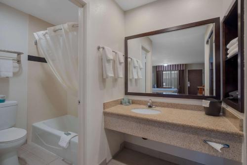 a bathroom with a sink and a toilet and a mirror at Best Western Norwalk Inn in Norwalk