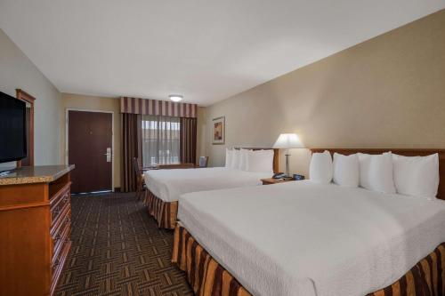 a hotel room with two beds and a flat screen tv at Best Western Norwalk Inn in Norwalk