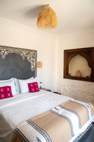 a bedroom with a large bed with red pillows at Dar El Mandar - Ferme & Table d'Hôte Berbère in Bhalil