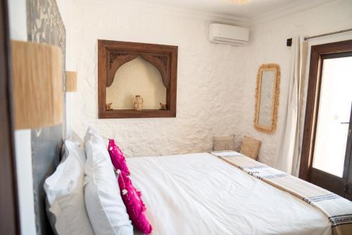 a bedroom with a bed with white sheets and pink pillows at Dar El Mandar - Ferme & Table d'Hôte Berbère in Bhalil