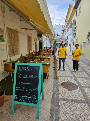 a couple of men walking down a street with a restaurant at Residence Pé na Areia in Albufeira