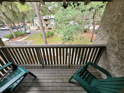 two green benches sitting on a wooden porch at Tranquility in paradise- 2 bedroom villa w/parking in Hilton Head Island