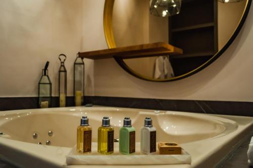 Un baño con una bañera con cuatro botellas. en Casa Raíces Hotel Luxury & Viñedo en Los Galvanes