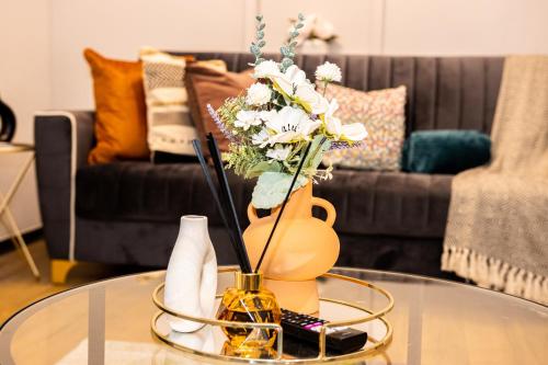 une table en verre avec un vase et des fleurs. dans l'établissement TD Stourb Dudley - Luxurious 3 Bedroom House - Sleeps 7 - DY1 - Long Stay for Contractors & Families, à Woodside