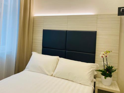 un letto con lenzuola bianche e una testiera blu di Hotel Fioralba a Milano