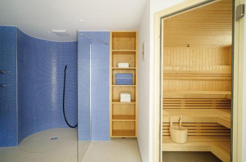 a bathroom with a shower with blue tiles at Alpenhof Apartments Oberstdorf in Oberstdorf