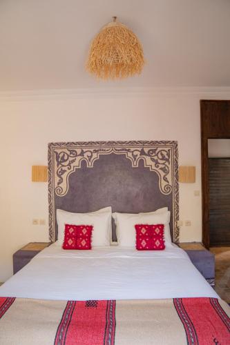 a bedroom with a large white bed with red pillows at Dar El Mandar - Ferme & Table d'Hôte Berbère in Bhalil