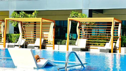 a person sitting in a chair next to a swimming pool at The Shrashi Suites, Dubai Creek Harbour - Paradise on the Island with Dubai Skyline & Burj Khaleefa View in Dubai