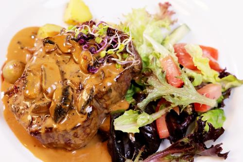 a plate of food with meat and a salad at Northridge Golf Resort in Orewa