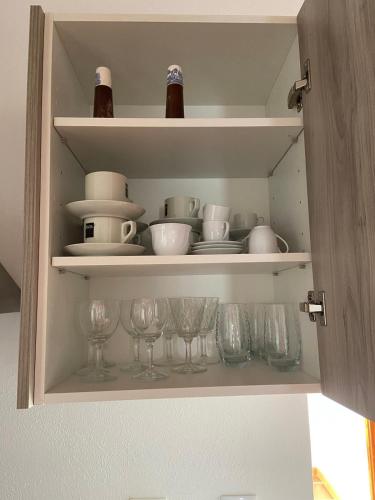 a cupboard with dishes and wine bottles and glasses at Casinhas Alegria in São Marcos do Campo