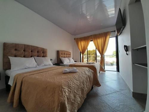 a bedroom with two beds and a flat screen tv at Katara Boutique Hotel in Mariquita
