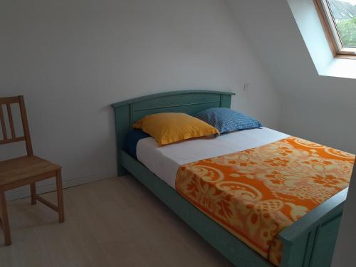 a bed with a green headboard and a chair in a room at la maison de l'Harmadas in Parigné-lʼÉvêque