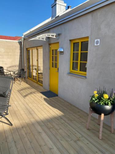 a deck with a yellow door and a table and chairs at Casa Annie & Nadja - Toppmodernt centralt i Borgholm in Borgholm