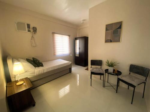 um quarto com uma cama, 2 cadeiras e uma mesa em Cresta Dormitory em Dumaguete