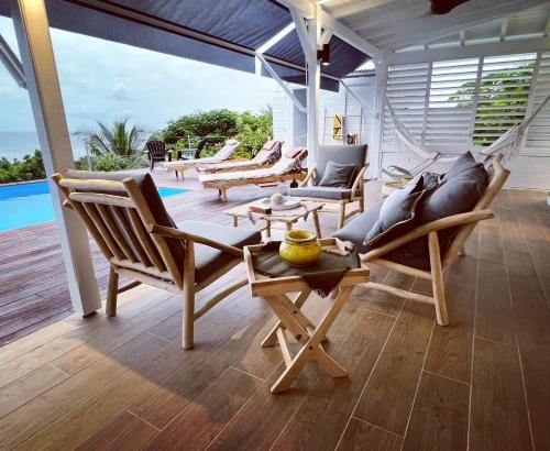 a porch with chairs and a hammock and a pool at La Villa By Ferdi'Nan in Grand-Bourg