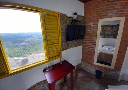 a room with a window and a chair and a television at Pousada do Xerife in Caconde
