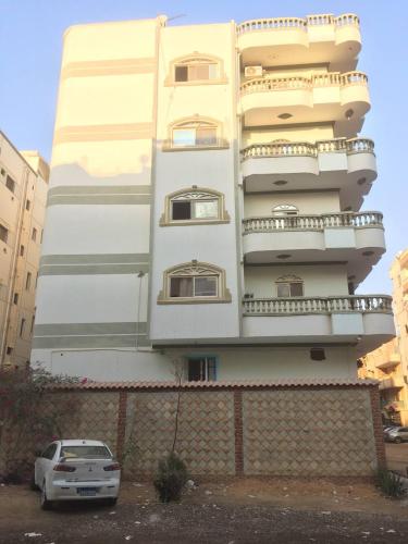 Un bâtiment blanc avec une voiture garée devant. dans l'établissement عقار السلام, à Kafr Rāshid