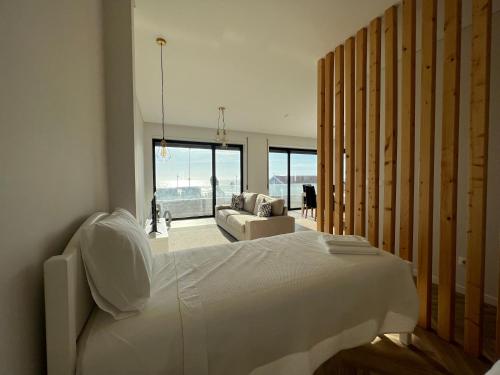 um quarto com uma grande cama branca e um sofá em Custódio Ocean View na Praia de Mira