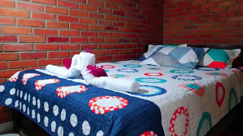a bed with a blue and white blanket and a brick wall at Cabaña la Hamaca Grande un encuentro con la naturaleza in El Zaino