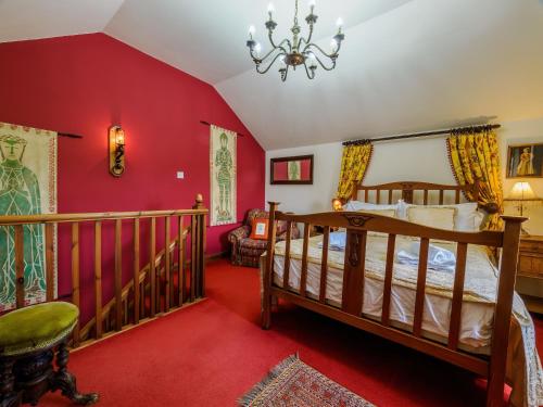 een slaapkamer met rode muren en een bed en een kroonluchter bij Sweet knoll cottage in Buxton