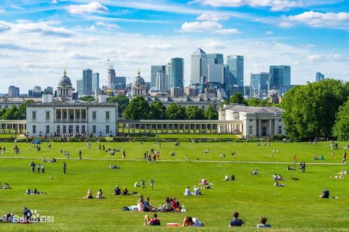 um grupo de pessoas sentadas num campo em frente a um edifício em Luxury Flat Near Greenwich Park em Londres