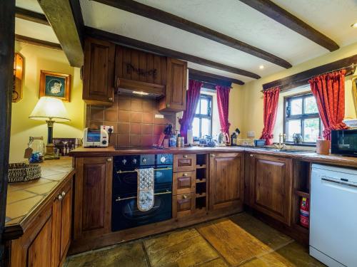 cocina con armarios de madera y lavavajillas azul en Sweet knoll cottage, en Buxton