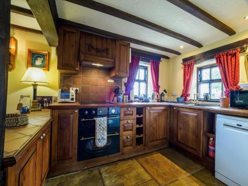 a kitchen with wooden cabinets and a blue dishwasher at Sweet knoll cottage in Buxton