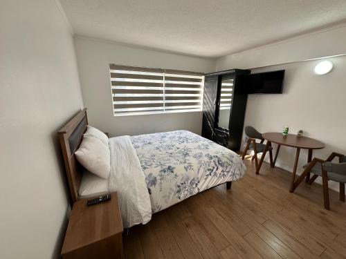 1 dormitorio con cama, mesa y ventana en TinyApartments - estudio pleno centro Concepción en Concepción