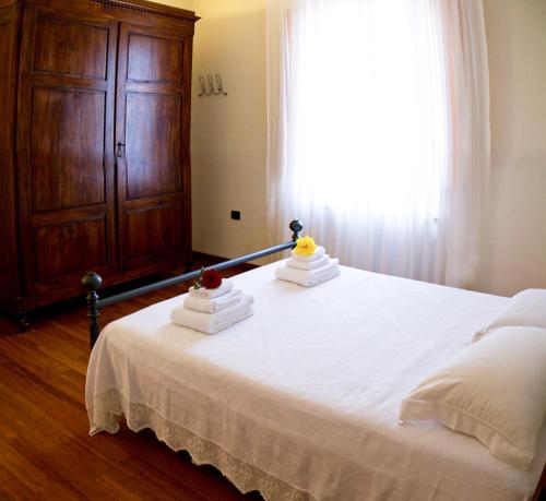 a bedroom with a white bed with a wooden cabinet at B&B Il Ramaiolo in Santa Maria a Monte