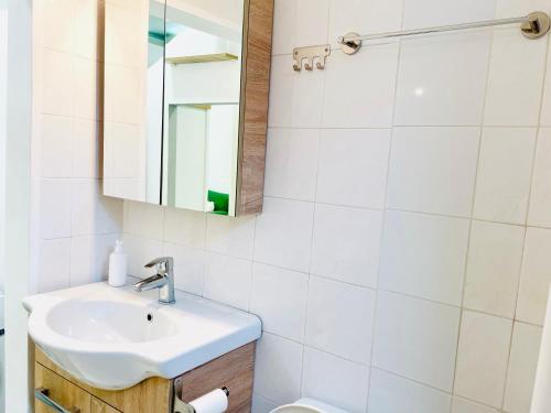 een witte badkamer met een wastafel en een spiegel bij Ithaca: Διαμέρισμα με αυτόνομη είσοδο. in Thessaloniki