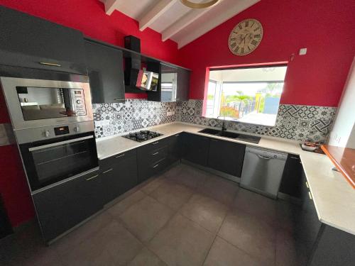 a kitchen with red walls and a clock on the wall at Les cocotiers d'Aladya in Lamentin