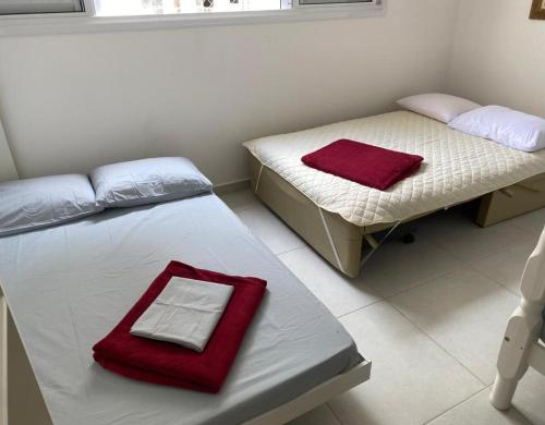 two beds in a room with a red towel on it at Studio2 Condomínio da Fé Cachoeira Paulista in Cachoeira Paulista