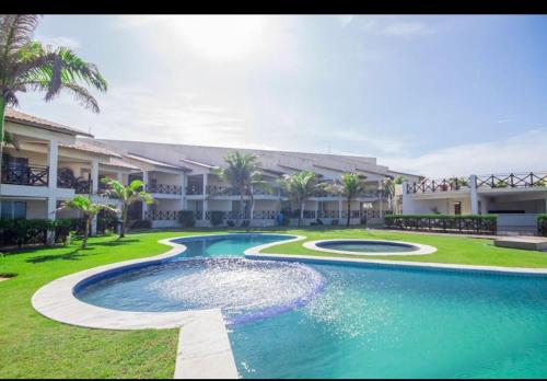 a resort with a swimming pool in front of a building at Paraíso a beira-mar na praia de Búzios/RN in Nísia Floresta